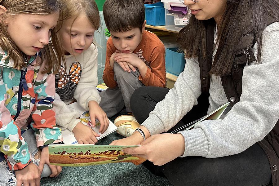 Rosa Solis'26 reads ¿De dónde eres? to three Todd Elementary students.